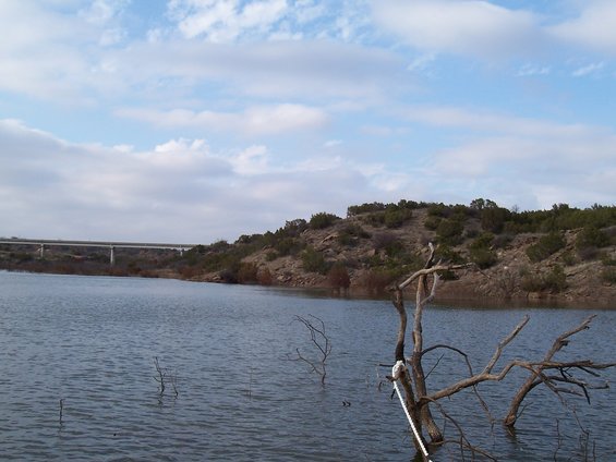Lake with a bridge and trees on the shore under a cloudy sky