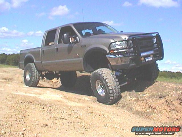 Tan lifted pickup truck with bull bar on dirt terrain
