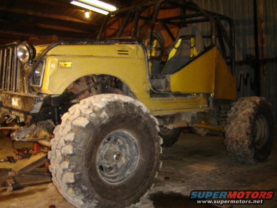 Yellow off-road vehicle with a roll cage and large tires, parked indoors