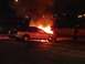 1979 Ford Bronco - A car is ablaze at night, with a firefighter observing the scene.