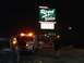 1979 Ford Bronco - A tow truck attends to a car at night near a brightly lit sign.