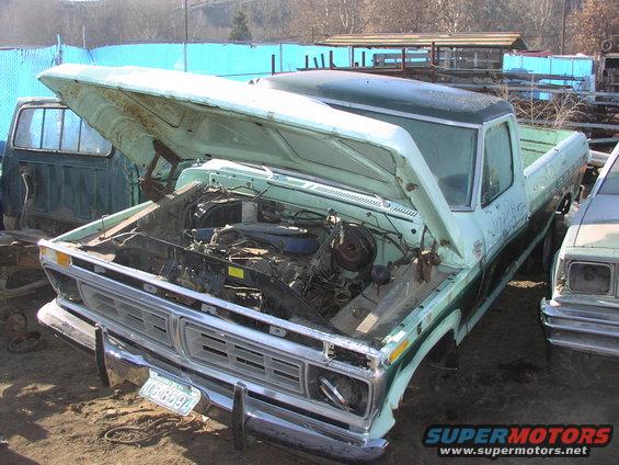 1977 Ford F-150 pickup truck with hood open, showing engine. Another vehicle is parked to the right