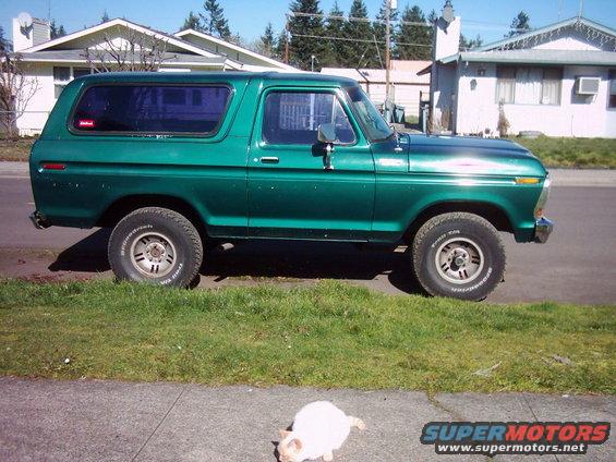 1978 Ford Bronco parked on street, side view. Green paint, tinted windows