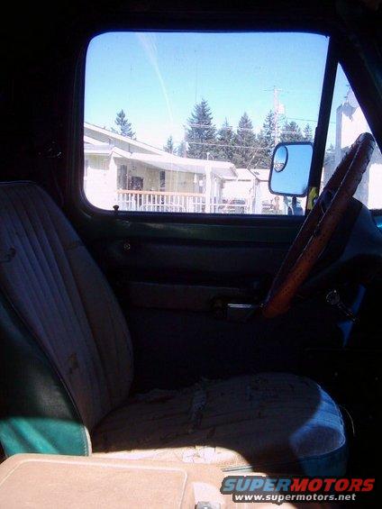 1978 Ford Bronco interior showing worn seats, wooden steering wheel, and a side mirror
