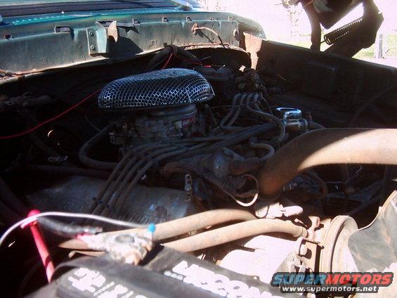 Engine bay with a V8 engine, air cleaner, and battery visible. Some wiring and hoses are present