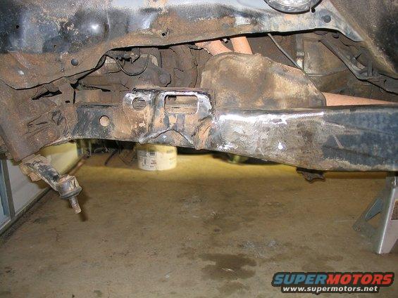 rusted truck frame section with suspension components visible, supported by jack stands