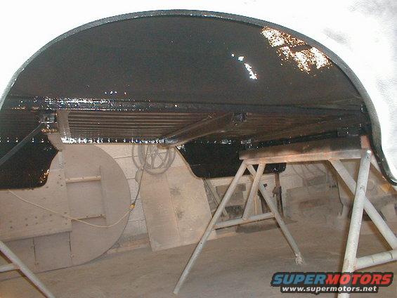Underbody of a vehicle on jack stands, showing black coating and some structural components
