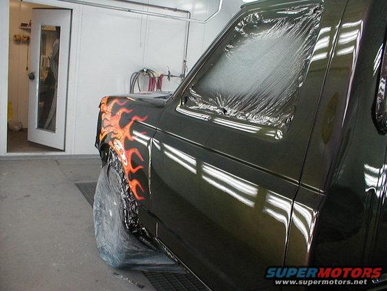 1991 Ford F-150 fender with flame paint, covered in plastic in a paint booth