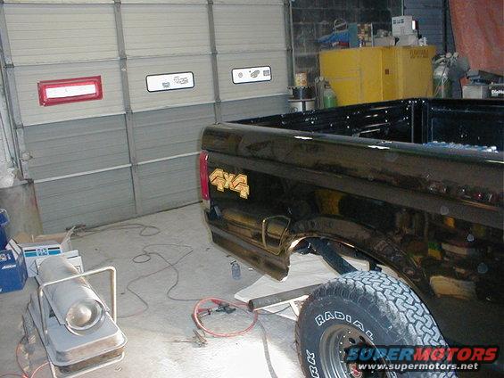 Black Ford F-150 pickup truck rear quarter panel with 4x4 decal, parked in garage