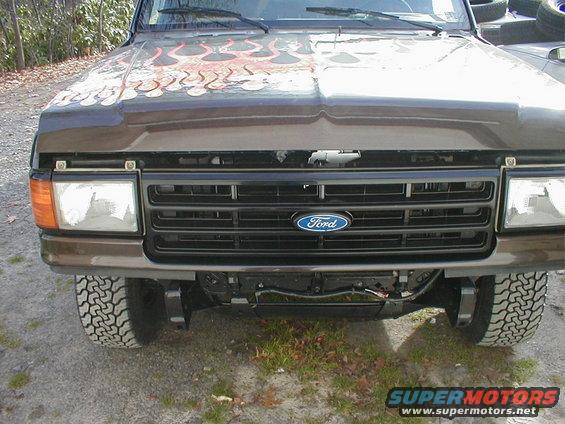 Front view of a brown 1991 Ford F-150 with flame decals on the hood and a Ford emblem on the grille