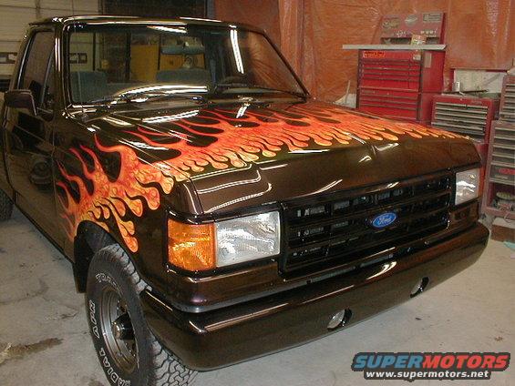 Dark brown 1991 Ford F-150 truck with orange and yellow flames painted on the hood and fender