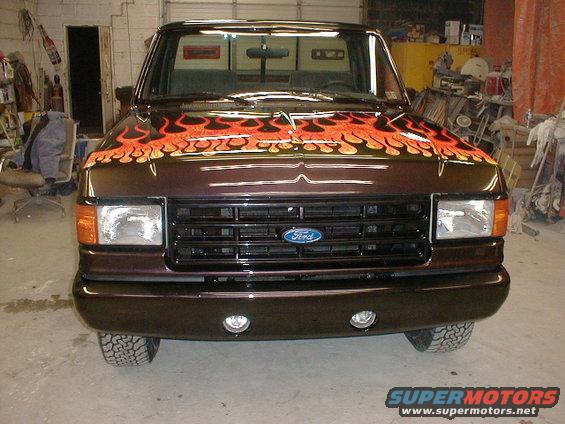 Dark brown 1991 Ford F-150 truck with orange and yellow flames painted on the hood, viewed from the front