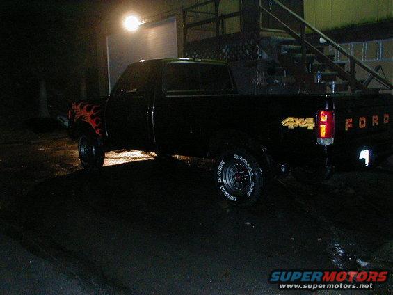 Black Ford F-150 pickup truck with flame decals on the front fender and 4x4 badging on the rear fender