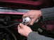 1994 Ford Bronco - A mechanic pours fluid from a can into a hose in the engine bay of a 1994 Ford Bronco.