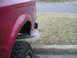 1994 Ford Bronco - Rear view of a red SUV, showing the quarter panel, tire, and exhaust pipe with visible smoke.