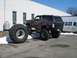 1994 Ford Bronco - This modified Ford Bronco sits high off the ground with its large tires, one of which is detached and resting beside the vehicle.