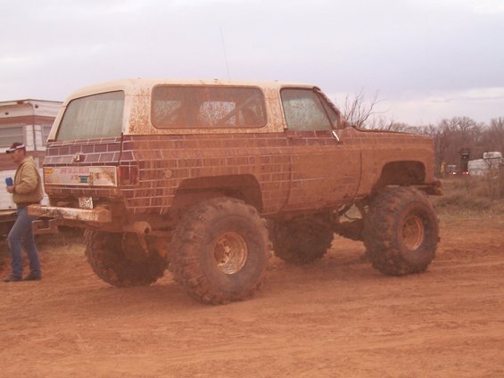 Mud-covered lifted SUV with large tires, seen from the rear