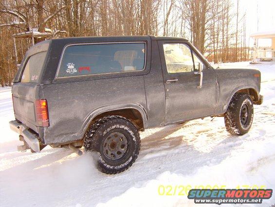 Gray Ford Bronco driving in snow, kicking up dust from rear tire