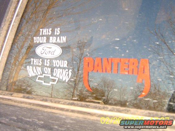 Car window with 'This is your brain' and 'This is your brain on drugs' stickers, a Ford oval, a Chevrolet bowtie, and a large orange 'PANTERA' decal