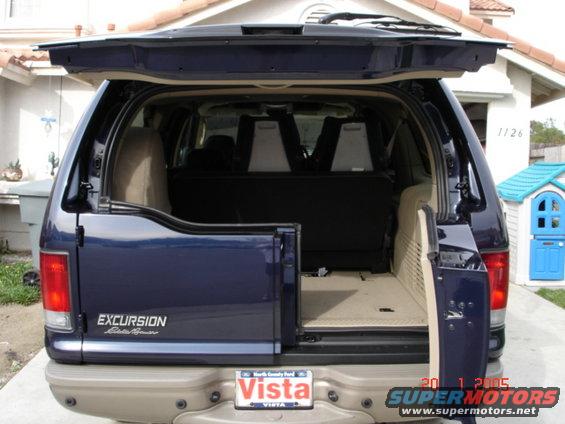 Rear view of a blue Ford Excursion Eddie Bauer with the tailgate open, showing the cargo area and third-row seats