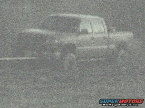Pickup truck parked in a grassy area. The image is grainy and lacks detail