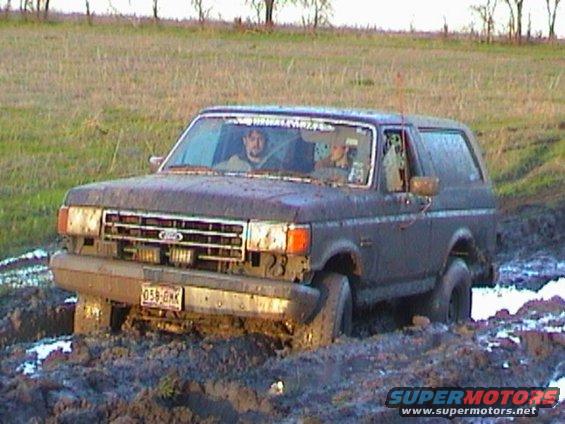 1989 Ford Bronco stuck in mud with two people inside