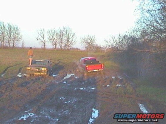 Two trucks stuck in mud, one red and one brown