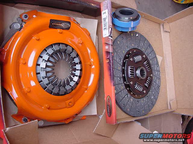 Orange clutch pressure plate, clutch disc, and release bearing in a cardboard box
