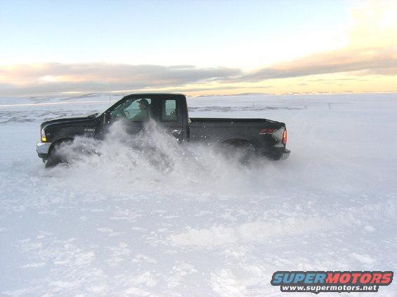 Black 2001 Ford F-250 Super Duty pickup truck drifts in snow