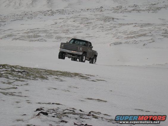 Gray pickup truck driving in snow, 1980s model