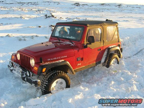 Red Jeep Wrangler Rubicon stuck in snow, front 3/4 view