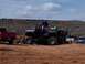 2004 Aston Martin Virage - Modified pickup truck with large tires and suspension, carrying people and a dirt bike in a muddy area.