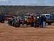 2004 Aston Martin Virage - Custom monster truck with flame decals and exposed engine sits in a sandy area with other vehicles and a train in the distance.