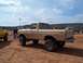 2004 Aston Martin Virage - A lifted tan Ford pickup truck sits on sandy terrain with other vehicles and spectators in the background.