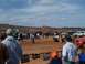 2004 Aston Martin Virage - Off-road vehicles and crowds at a mud bog event, with hills in the background.