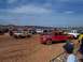 2004 Aston Martin Virage - A large gathering of trucks and SUVs in a muddy, outdoor setting under a partly cloudy sky.
