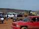 2004 Aston Martin Virage - A muddy scene with several trucks and a large yellow loader at an outdoor event.