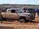 2004 Aston Martin Virage - Muddy Dodge Ram pickup truck is stuck in the sand during an off-road event.