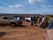 2004 Aston Martin Virage - Several vehicles and people are gathered in a sandy area, with one truck deeply stuck in the mud.