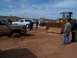 2004 Aston Martin Virage - A muddy pickup truck is stuck in the sand and being pulled by a large yellow front loader, with several people observing.