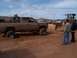 2004 Aston Martin Virage - Muddy pickup truck stuck in sand, assisted by a bulldozer at an outdoor event.