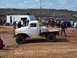 2004 Aston Martin Virage - A crowd watches a white flatbed truck navigate a muddy off-road course.