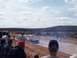 2004 Aston Martin Virage - Spectators watch a white pickup truck navigate a muddy track during an event.