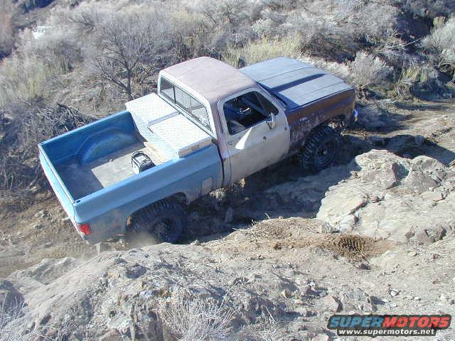 Pickup truck with a toolbox in the bed driving over rocks