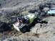 1978 Ford Bronco - A yellow off-road vehicle navigates a rocky trail, with a white pickup truck in the background.
