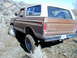 1978 Ford Bronco - A brown 1978 Ford Bronco navigates a dirt trail, showing its rear 3/4 profile.