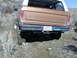 1978 Ford Bronco - Rear view of a 1978 Ford Bronco on a dirt trail with a spare tire inside.