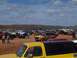 2004 Aston Martin Virage - A large gathering of off-road vehicles are parked in a dusty, muddy field under a partly cloudy sky.