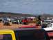 2004 Aston Martin Virage - A large gathering of off-road vehicles and heavy equipment is seen on a dusty lot with hills in the background.