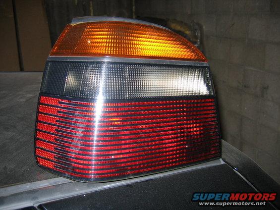 Close-up of a car's rear taillight assembly, showing red brake lights and amber turn signal
